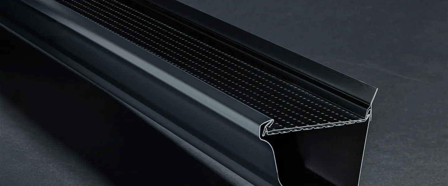 Alu-Rex Hover Pro floating gutter hanger with built-in dual-layer guard clipped onto a black hemmed-back gutter