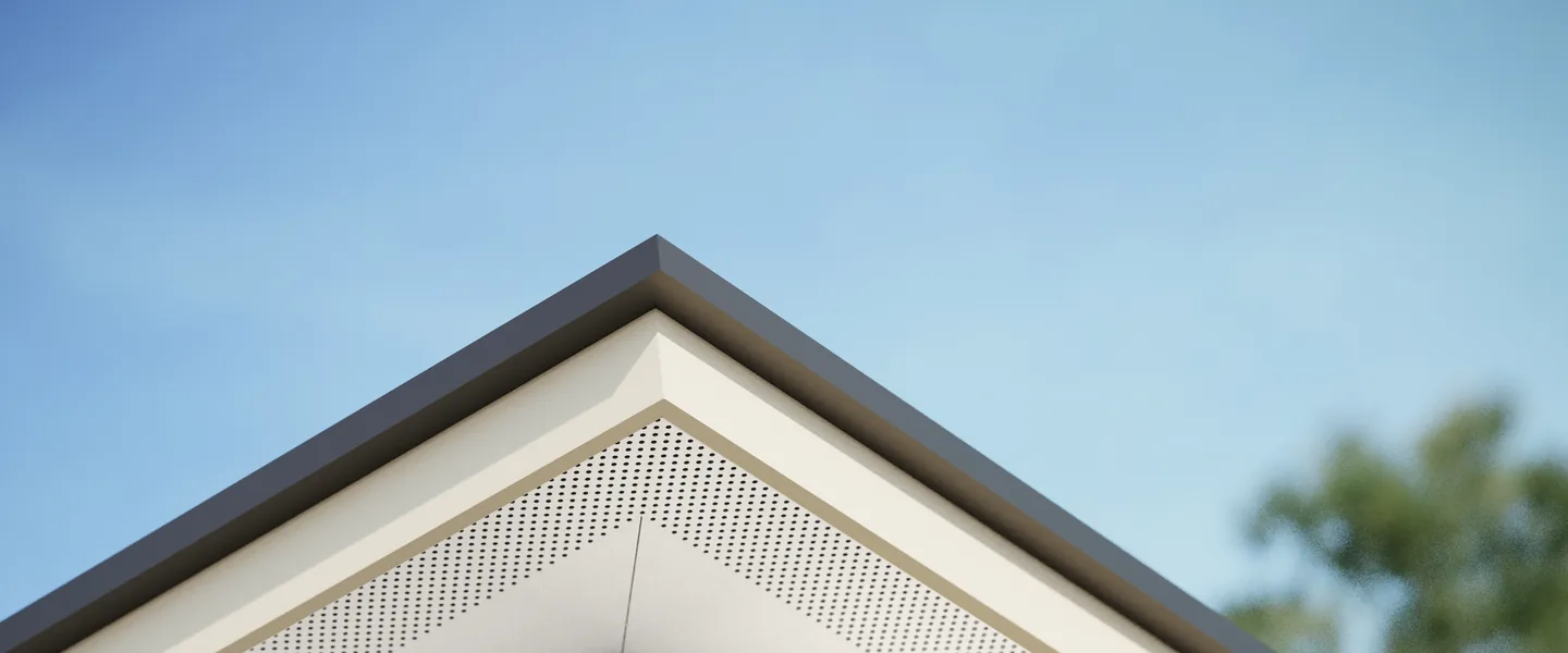 Underside of an eave corner finished in white vented Hardie Soffit, mitred at the corner, with a dark fascia against a blue sky